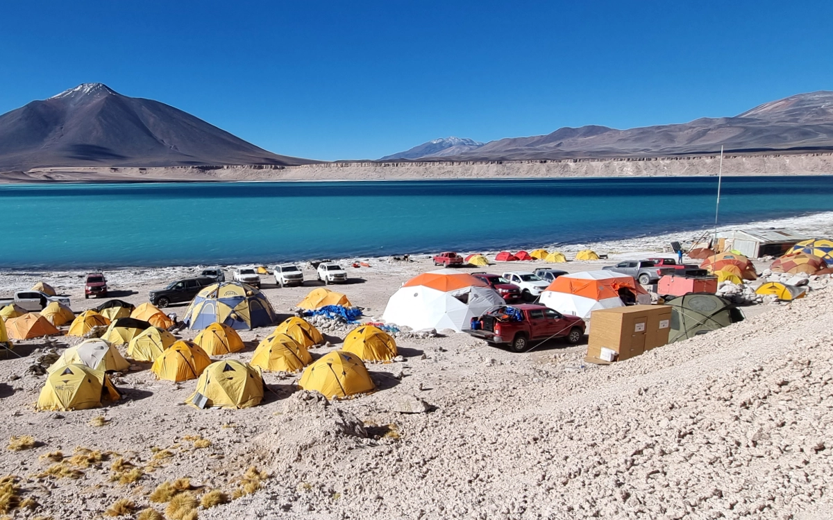 High-altitude expedition base camp with tents and 4x4 vehicles at Laguna Verde during the Ojos del Salado 14-day climb.